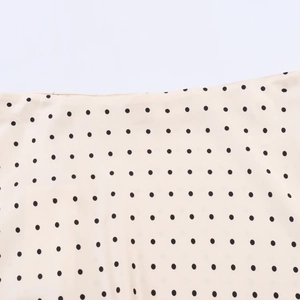 Détail macro du tissu en satin beige clair avec motif à pois noirs classique et élégant