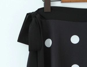 Détail d'une jupe noire à pois blancs avec un nœud décoratif élégant à la taille latérale