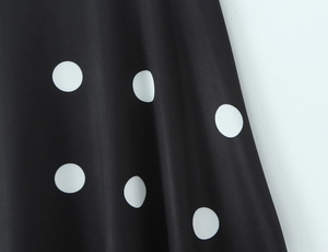Vue détaillée du tissu à pois noir et blanc avec plis élégants et un drapé fluide