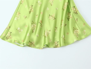Close-up of light green floral dress showing glossy satin fabric and rolled hem