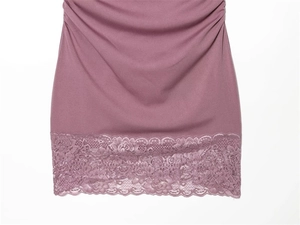 Detailansicht des staubrosa Kleidsaums mit floraler Spitze und plissiertem Stoff
