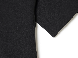Primer plano de las costuras y el tejido negro texturizado de la blusa con manga abullonada