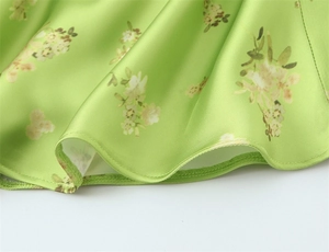 Detail shot of green floral silk dress showing smooth satin texture and neat hemline