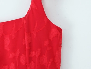 Close-up of red floral jacquard fabric showing detailed textured pattern on summer dress