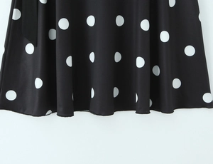 Gros plan sur un tissu noir à pois blancs avec ourlet drapé élégant et coutures soignées