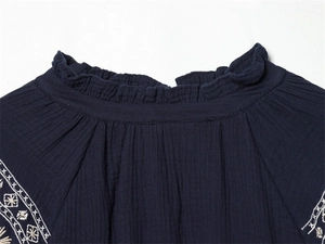 Close-up of navy blue shirt with ruffled collar and white ethnic embroidery on crepe fabric