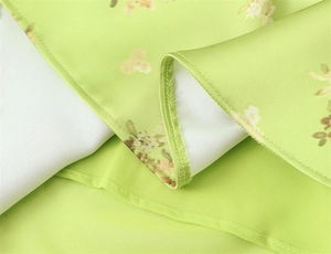 Detailed view of fine stitching and hemline on light green floral chiffon dress fabric