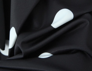 Vue détaillée du tissu à pois noirs et blancs avec une texture en maille élastique