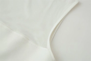 Detail of white bodysuit with translucent mesh and solid fabric patchwork stitching