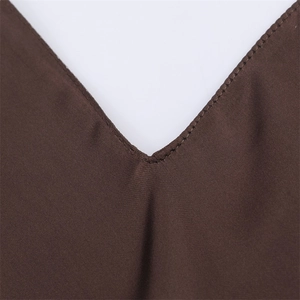 Close-up detail of the deep brown satin dress showing the V-neckline and refined stitching