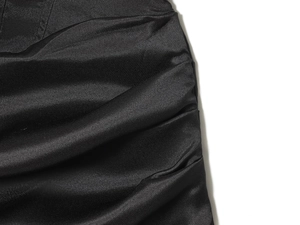 Close-up detail of glossy black ruched fabric and textured satin finish on the dress