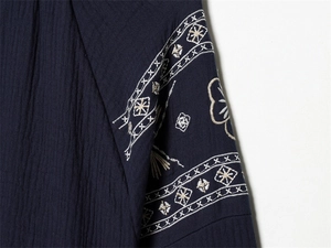 Detail of navy blue textured blouse featuring intricate cream floral sleeve embroidery