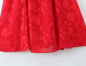 Detail of red floral burnout fabric with tiered layers and elegant textured patterns