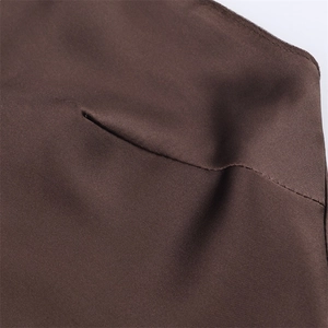 Detailed view of dark brown satin fabric texture and premium stitching on a fashion dress