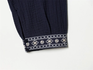 Detail of navy blue crinkle gauze shirt cuff with white geometric embroidery and buttons