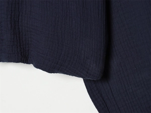 Macro detail of dark blue crinkle gauze fabric showing breathable double-layer texture