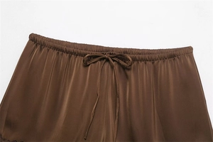 Detailed view of dark brown satin shorts featuring lace trim and a delicate drawstring bow