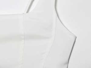 Detail van een witte midi-jurk met korsetnaden en hoogwaardige geweven textuur