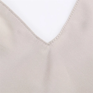 Detail of elegant V-neckline with fine stitching on beige satin texture fabric