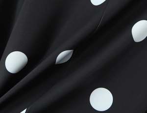 Gros plan d'un tissu à pois noirs et blancs avec texture lisse et plis doux