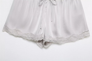 Detailed view of silver satin shorts featuring delicate lace trim and drawstring waist