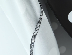 Détail rapproché de la couture surjetée sur le tissu en mousseline à pois noirs et blancs