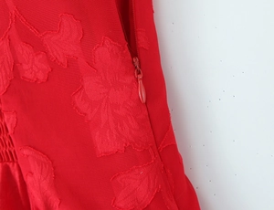 Close-up of red jacquard floral fabric detail with a seamless matching invisible zipper