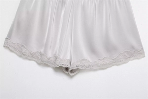 Detail of silver grey satin shorts featuring elegant eyelash lace trim along the hem