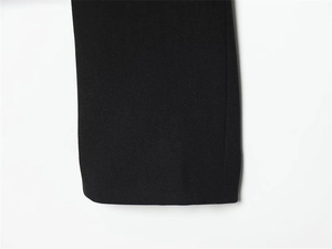 Close-up detail of smooth black fabric texture and clean stitched hem on the garment sleeve