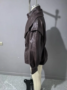 Detail of dark brown faux leather jacket featuring layered shoulders and pleated waist