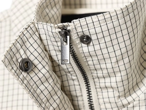 Detail of checkered nylon jacket showing the collar, metal zipper, and snap button closure