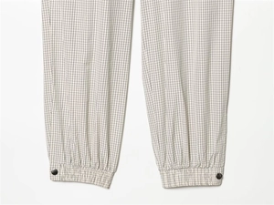 Close-up of checkered jogger pants with elastic cuffs and decorative metal snap buttons