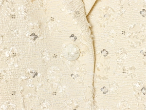 Macro shot of cream jacket fabric with textured weave, silver sequins and white pearls