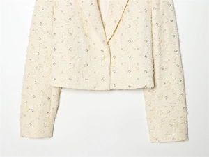 Close-up of cream-colored tweed blazer with shimmering silver sequins and crisp lapel