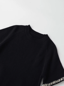 Dettaglio della maglia nera con ricami di perle e strass sulle maniche corte