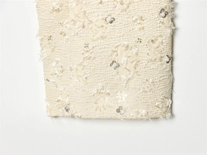 Macro shot of ivory jacket fabric with textured wave pattern, sequins, and pearl accents