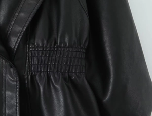 Detailed macro view of the elastic pleated waist and leather texture on a black PU jacket