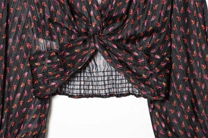 Detail of V-neck floral blouse with twisted hem and elastic gathered waist texture