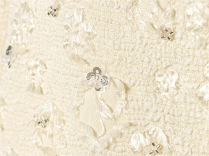 Macro shot of elegant cream fabric with floral sequins, beads and tactile fringe detail