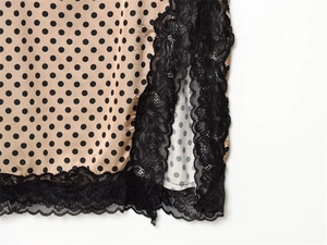 Detail of champagne satin dress hem featuring black polka dots and floral lace trim