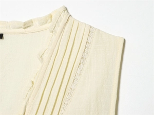 Détail du col à volants avec tissu plissé et dentelle délicate sur chemisier beige