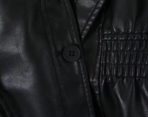 Detailed macro view of black faux leather jacket featuring smocking and a matte button