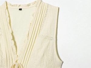 Détail du haut crème sans manches avec broderie en dentelle et encolure à volants