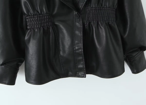 Close-up of the elasticated smocked waist and button detail on black faux leather jacket