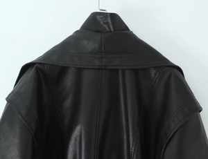 Detail view of the wide lapel collar and fine leather texture on a black faux leather jacket