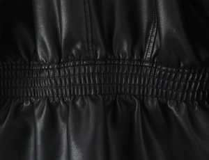 Macro view of elasticated ruched hem and pebbled texture on black faux leather jacket
