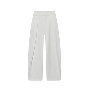 Détail du pantalon blanc taille haute avec plis sur le devant et tissu fluide drapé