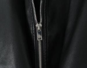 Detailed macro shot of a sleek silver metal zipper on a premium black leather jacket