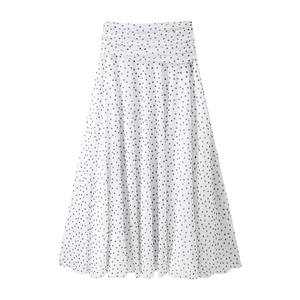Detail view of the pleated waistband and black polka dot pattern on a white midi skirt