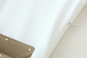 Détail macro d'une robe blanche côtelée avec fermeture invisible et rivets dorés